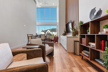 A living room with a large window and a view of a house across the street.